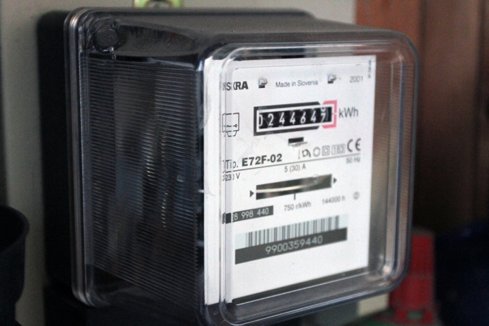 Régi, elektromechanikus fogyasztásmérő forgó számlappal.